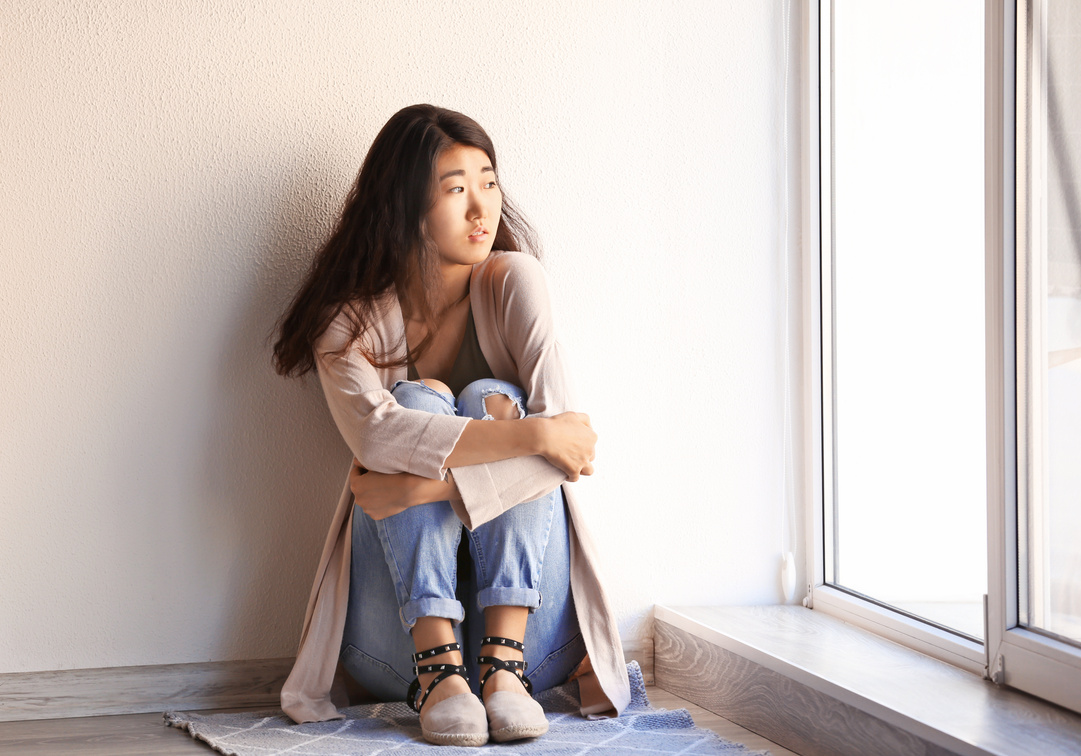 A Worried Female Teenager Sitting by the Window