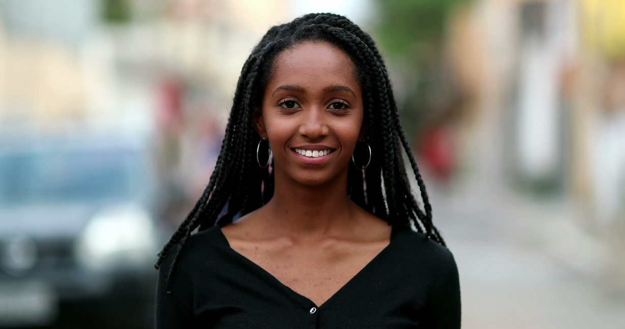 Portrait black African teen girl smiling at camera. Young woman face close-up